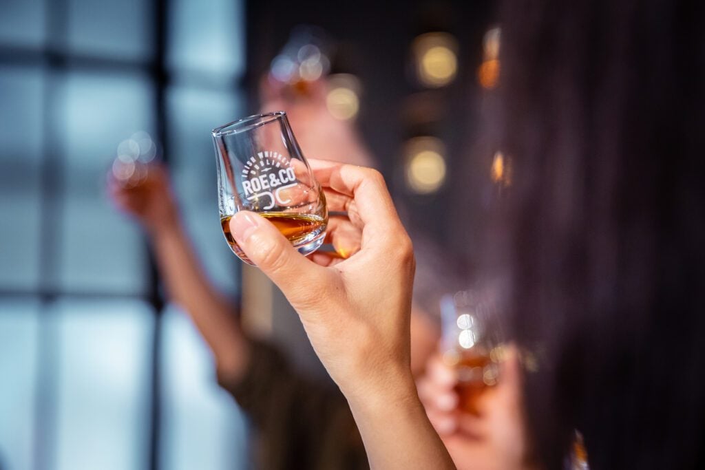 Roe & Co Distillery hand holding a nosing glass with roe & co Distillery logo